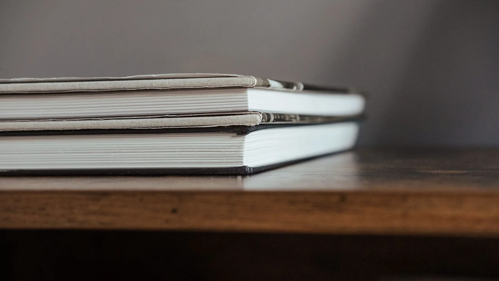 Hardcover books stacked on a wooden table Hardcover books stacked on a wooden table