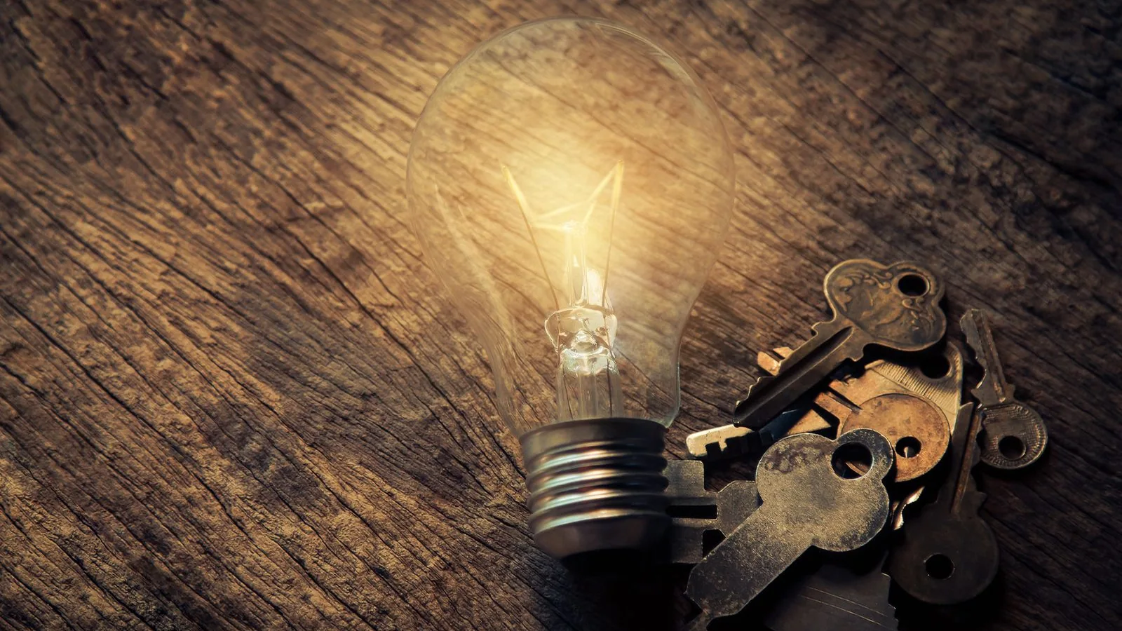 Keys beside a light bulb on a wooden table