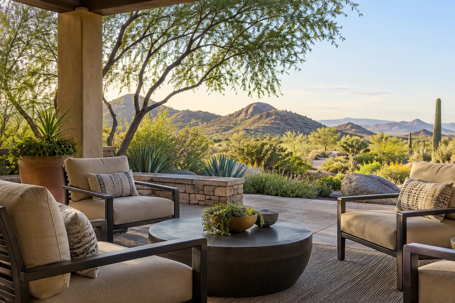 Shaded patio overlooking desert mountains Cushioned chairs surround a round coffee table on a shaded patio overlooking desert plants and rocky mountains.